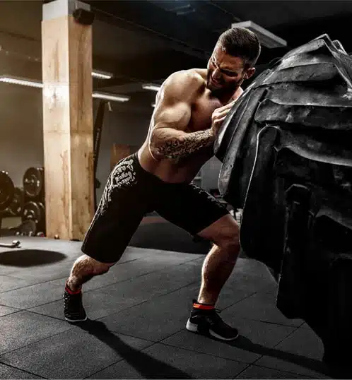 Brawny man lifting a truck tire in a gym