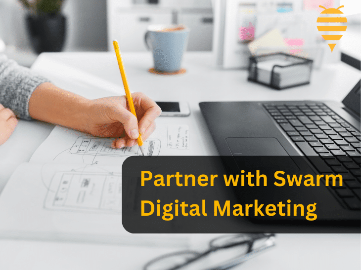 this graphic features a web designer specialist at a white desk drawing a mobile template on a page for a new client. There is overlay text advising business owners to partner with swarm digital marketing. In the top right is the swarm digital marketing logo.